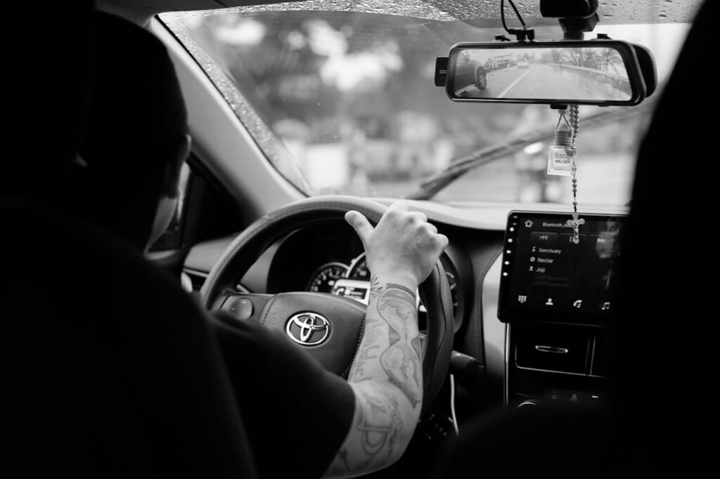 Demo Post 2 Monochrome image featuring a driver in a Toyota car interior, showcasing a focused driving experience.