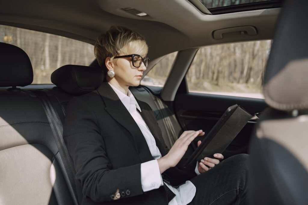 Demo Post 1 Side view of focused female in stylish formal clothes using tablet while riding on backseat of modern car